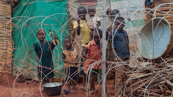 A displaced family stands behind the razor-wire that surrounds the United Nations' protected camp in Wau, South Sudan, in 2014.