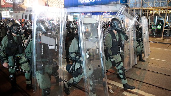 Police officers advance on a street facing protesters in Hong Kong.