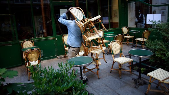 A cafe employee carries chairs as he setting up a terrace in Paris. 