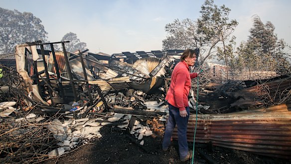 A resident hoses down a shed destroyed by the fire at Bomaderry. 