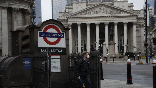 A man walks out of Bank underground train station backdropped by the Royal Exchange in the London. 