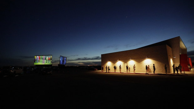 Using social distancing practices, moviegoers wait in line at the concession stand at the Stars and Stripes Drive-In Theatre that reopened in New Braunfels, Texas.