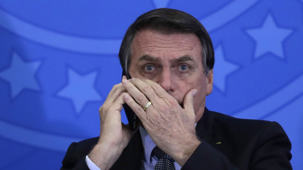 Brazilian President Jair Bolsonaro talks on his mobile phone during a ceremony at Planalto presidential palace in Brasilia.