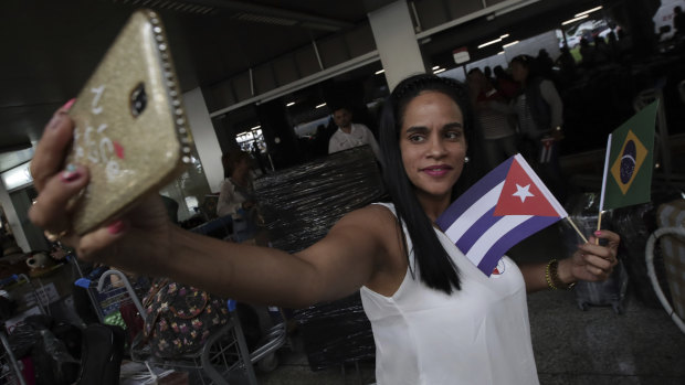 A Cuban doctor holding Brazilian and Cuban flags takes a selfie before she and other Cuban physicians return home at the airport in Brasilia.