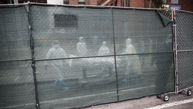 Medical staff move a body behind a fence at The Brooklyn Hospital Centre last week.