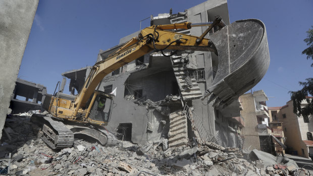 An excavator is used by a rescue worker to remove the rubble of buildings hit by Israeli airstrikes in Qana.