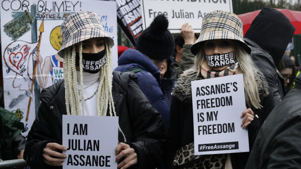 Two supporters wear masks and hold signs during a protest against the extradition of Wikileaks founder Julian Assange outside Belmarsh Magistrates Court in London in February.