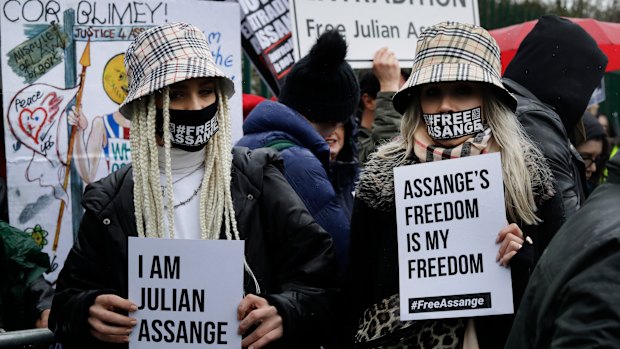 Two supporters wear masks and hold signs during a protest against the extradition of Wikileaks founder Julian Assange outside Belmarsh Magistrates Court in London in February.