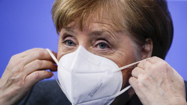 German Chancellor Angela Merkel puts on a face mask after a news conference on further coronavirus measures on Tuesday.