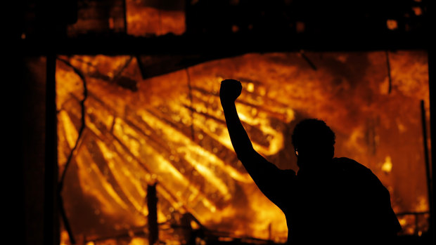 A protester gestures in front of the burning third precinct building of the Minneapolis Police Department on Thursday.