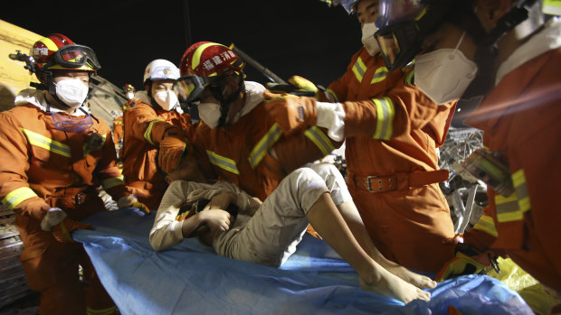 Rescuers place a boy pulled from the rubble of a collapsed hotel on a stretcher in Quanzhou, south-east China.
