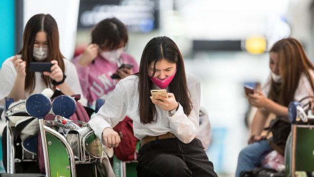 Travellers arrive at Melbourne Airport wearing face masks .