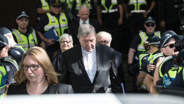 Police provide a barrier for the cardinal as he leaves the Magistrates Court on Tuesday.
