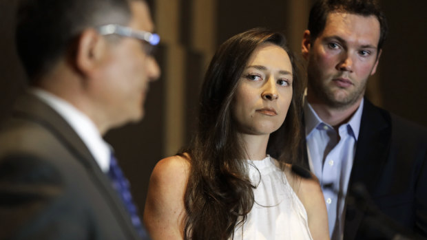 Olympic swimmer Ariana Kukors Smith, center, stands with her husband, Matt Smith, right, as they listen to Ray Mendoza, left, a member of her investigative team, as he talks to reporter.