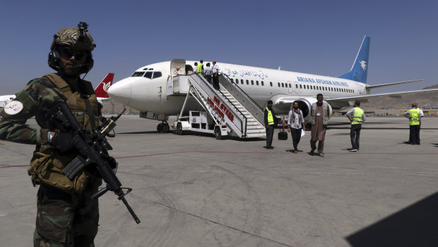 A Taliban soldier stands guard as passengers disembark on arrival from Kandahar, at Hamid Karzai International Airport in Kabul, Afghanistan, on Sunday.