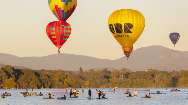 The ACT government's new CBR brand hot air balloon, right, is seen flying over Lake Burley Griffin at this year's Canberra Balloon Spectacular.