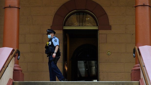A masked officer at the entrance of NSW Parliament House.