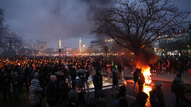 People gather in Place De La Nation as smoke rises from small fires that were lit at the end of a demonstration in Paris. 