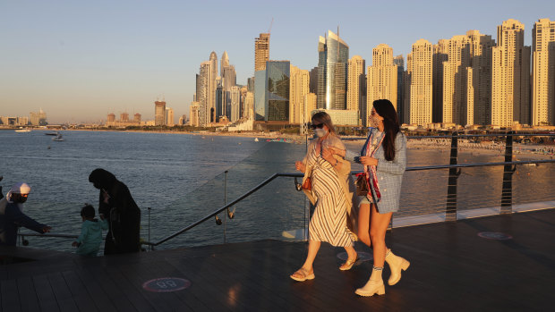 Tourists walk by an Emirati family in Dubai, United Arab Emirates.
