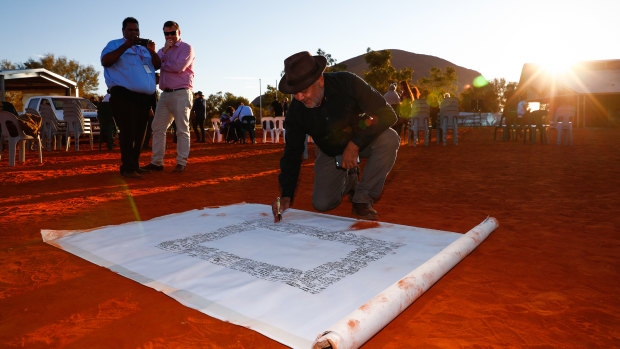 Noel Pearson signs the canvas for the Uluru Statement from the Heart.