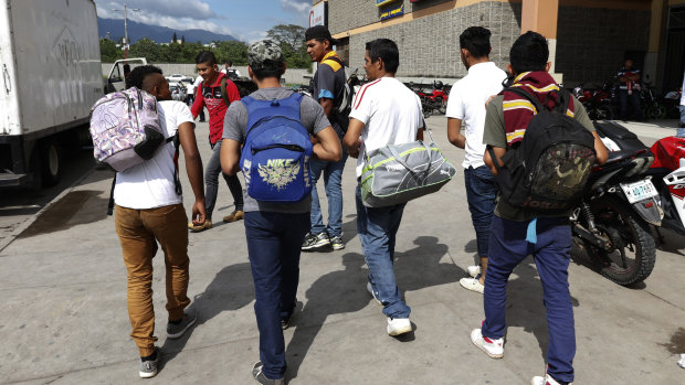 A group of young men arrive at a  bus station in San Pedro Sula, Honduras, to join scores of other migrants forming a caravan to travel to the US border on Monday.