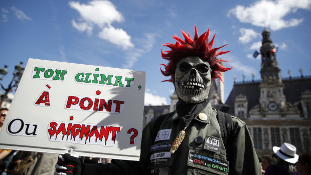 A man holds a poster reading: Your climate. Well done or rare? during a protest, in Paris, on Saturday.