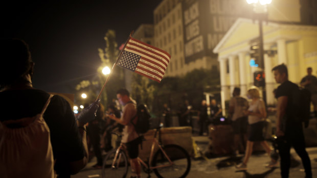 A protester holds an upside-down American flag inscribed with 'Black lives matter' during protests on Independence Day in a Washington street recently renamed Black Lives Matter Plaza.