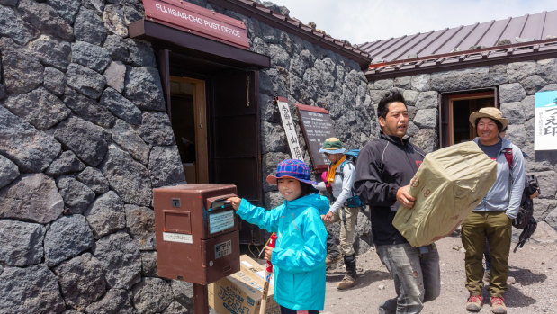A young hiker uses the mailbox outside the post office on the summit of the volcano.