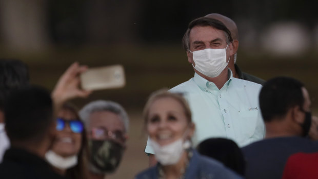 Supporters pose for a selfie with infected Brazilian President Jair Bolsonaro on Wednesday. Bolsonaro on the weekend said he has been cured.