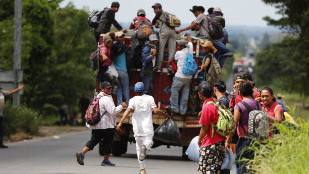A migrant runs to catch a ride as his fellow Central American migrants, part of the caravan hoping to reach the US border, get a ride.