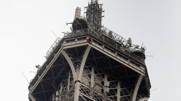 A rescue worker hangs from the Eiffel Tower.
