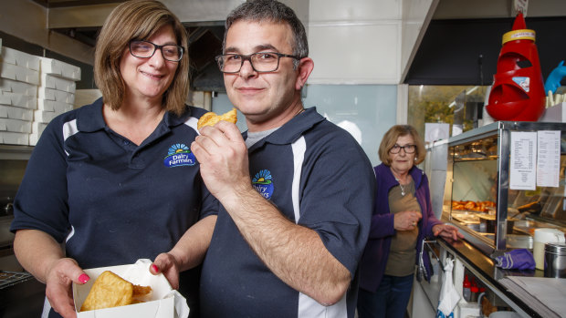 Hughes Takeaway owners Nita and Peter Dorizas with their much-loved potato scallops. Peter's mum Gina (in the background) is a crucial part of  the takeaway's potato scallop process.