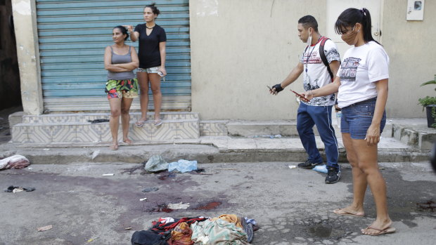 Residents take pictures of blood on the street after the shoot-out in the Jacarezinho favela.