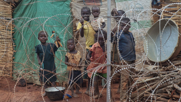A displaced family stands behind the razor-wire that surrounds the United Nations' protected camp in Wau, South Sudan, in 2014.