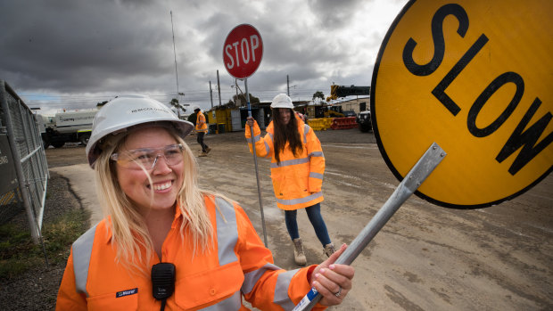 Rebecca Longo and Sherydan Fitzgerald direct traffic near a level crossing being constructed in Laverton, Victoria.