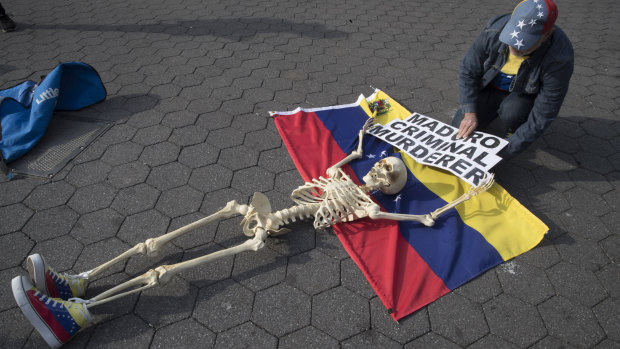 A supporter of Venezuelan opposition leader Juan Guaido secures a skeleton to a Venezuelan flag during a rally in New York's Union Square.