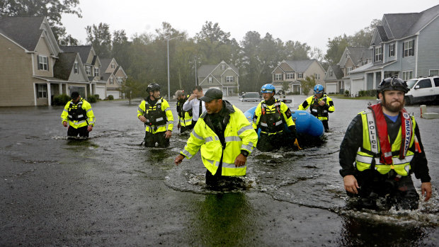 Members of the North Carolina Task Force urban search and rescue team wade through a flooded neighborhood.