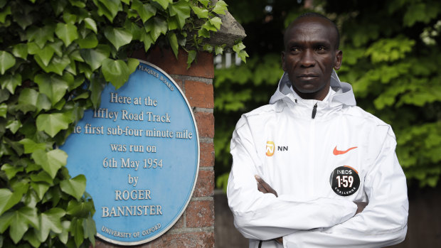 Eliud Kipchoge poses alongside a plaque commemorating Roger Bannister's four-minute mile.