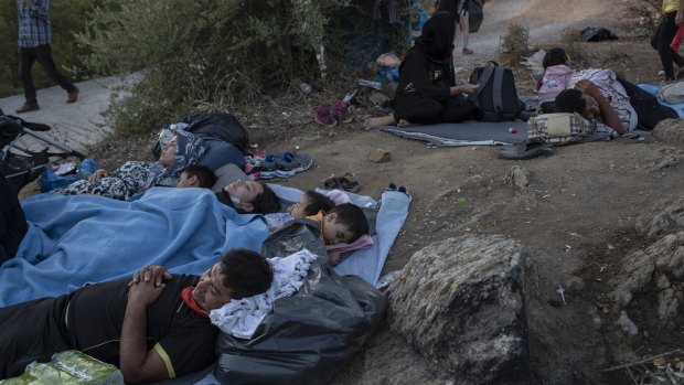 Migrants sleep outside the burned Moria refugee camp.