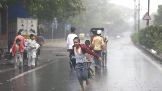 A boys runs in the middle of a street as others play during a sudden rain and dust storm amid India's lockdown in Delhi, India.