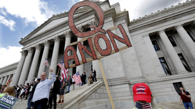 A demonstrator holds a QAnon sign as he walks at a protest opposing Washington state's stay-home order. 