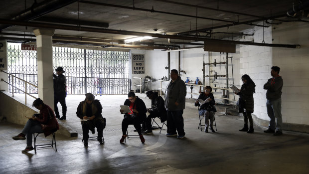 Hospitality workers wait in line in a basement garage to apply for unemployment benefits in Los Angeles.