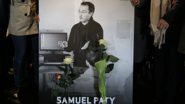 People hold a photo of the history teacher Samuel Paty during a memorial march in Conflans-Sainte-Honorine, north-west of Paris. 