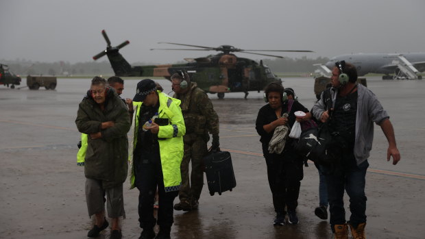 An Australian Army aircrewman and Queensland Police Service officers assist south-east Queensland residents rescued by an Australian Army MRH-90 Taipan helicopter.