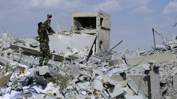 A Syrian soldier films the damage of the Syrian Scientific Research Centre.