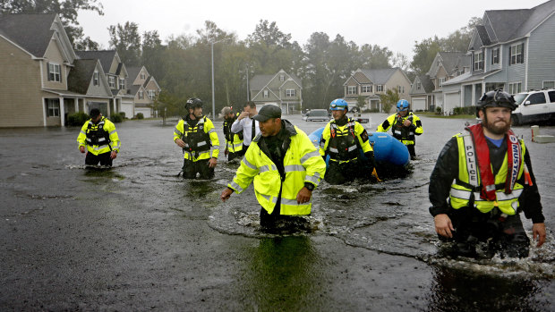 Members of the North Carolina Task Force urban search and rescue team wade through a flooded neighborhood.