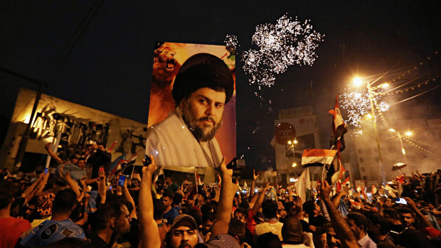 Supporters of Shiite cleric Muqtada al-Sadr carry his image as they celebrate in Tahrir Square, Baghdad, in May. 