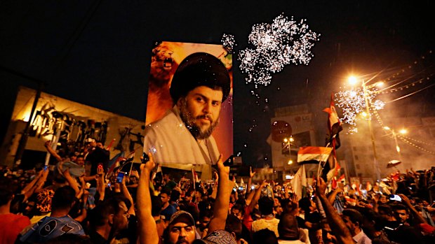 Supporters of Shiite cleric Muqtada al-Sadr carry his image as they celebrate in Tahrir Square, Baghdad, in May. 