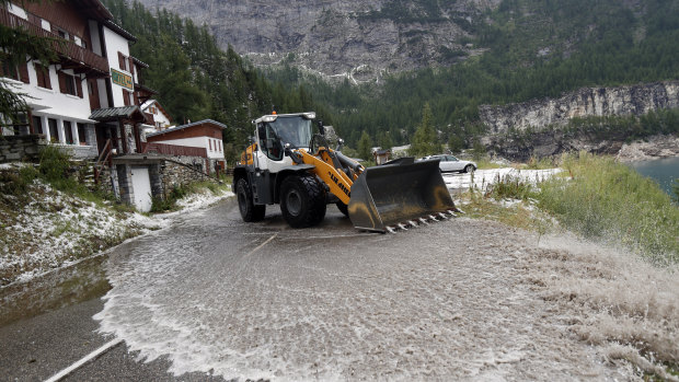 A worker uses a snow shovel to clean the road of the nineteenth stage of the Tour de France.