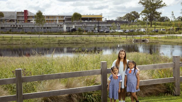 Charelle with her daughters Azalea and Isabella in front of Gledswood Hills Public School, which has 13 demountables despite only being opened a year ago